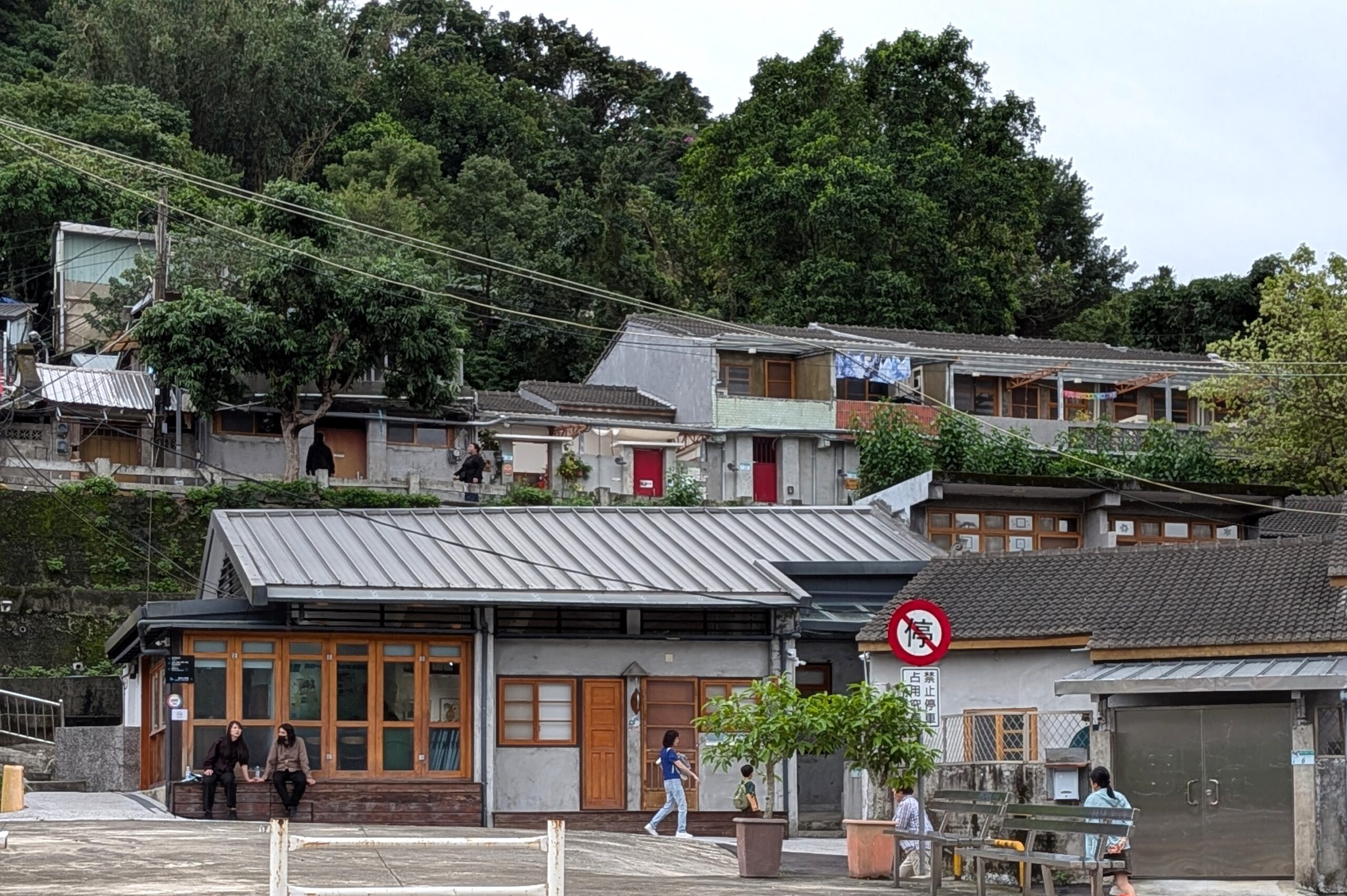 煥民新村の広場に面してリノベーションされた住宅群と、その背後の斜面に密集する住宅の景観。