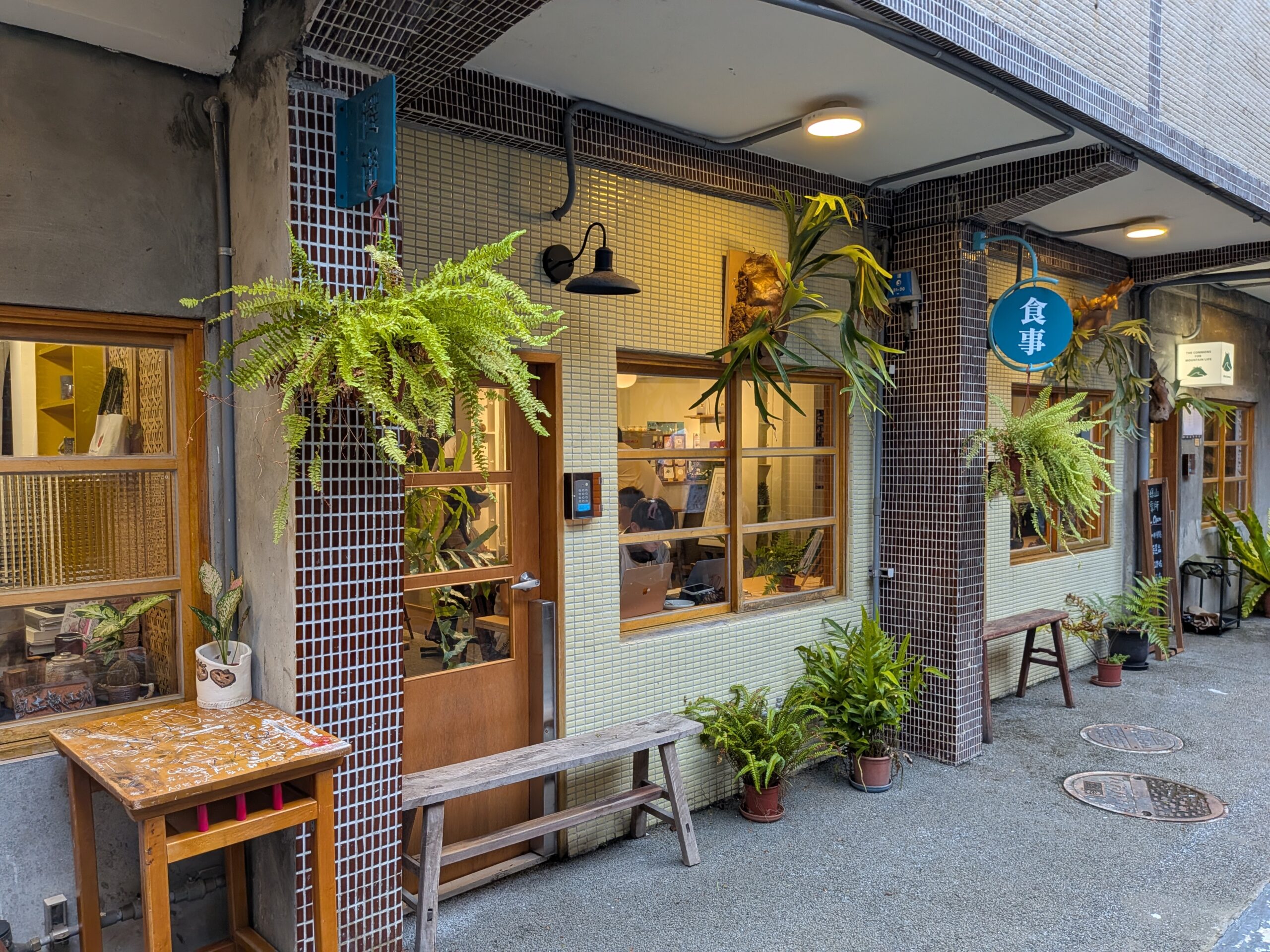 小さなタイル張りの外壁と木製建具を生かし、軒先に植物や照明を配置した煥民新村の店舗。