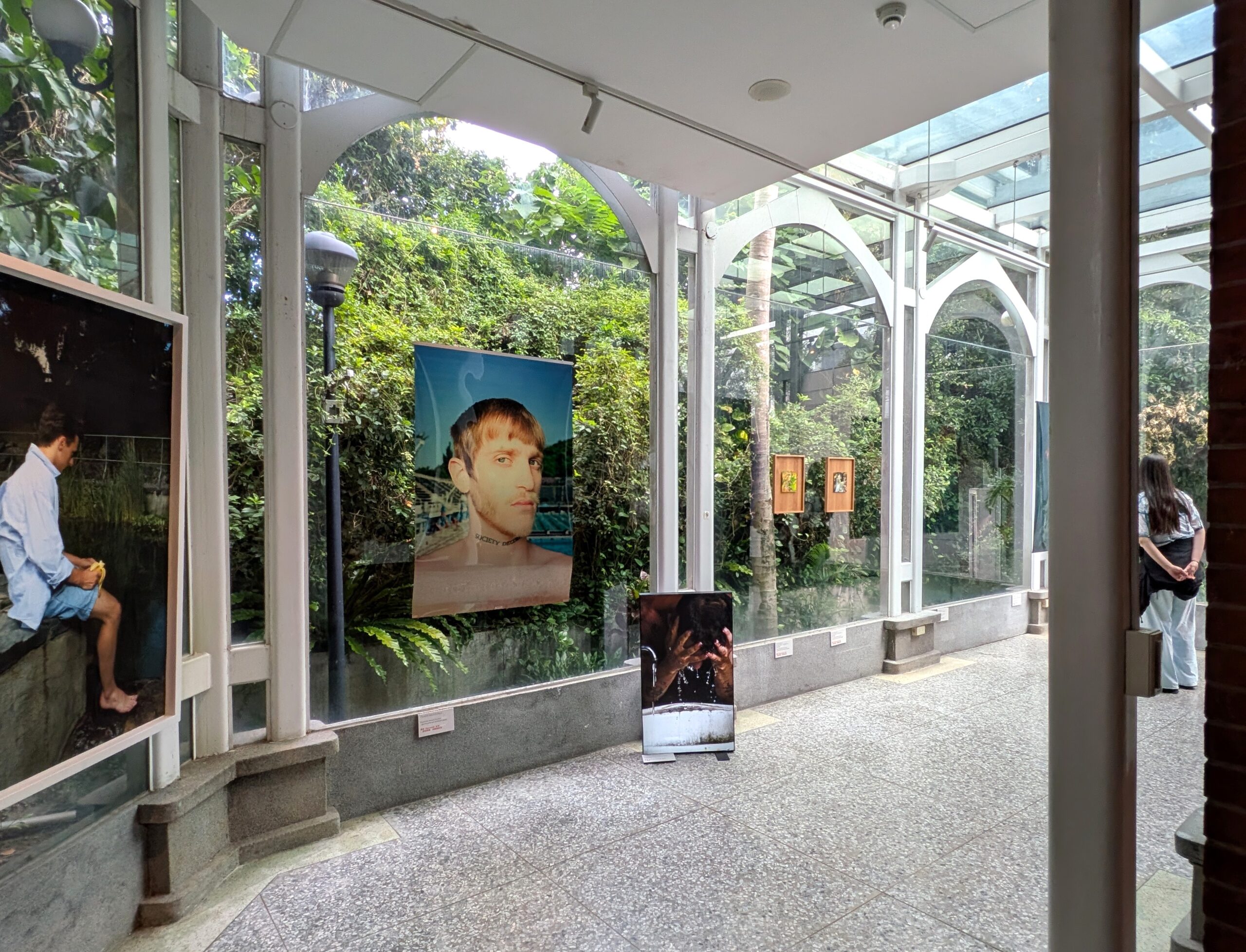 大きなガラス窓から豊かな緑が見え、屋外の景観と展示作品が一体となった明るい展示空間。