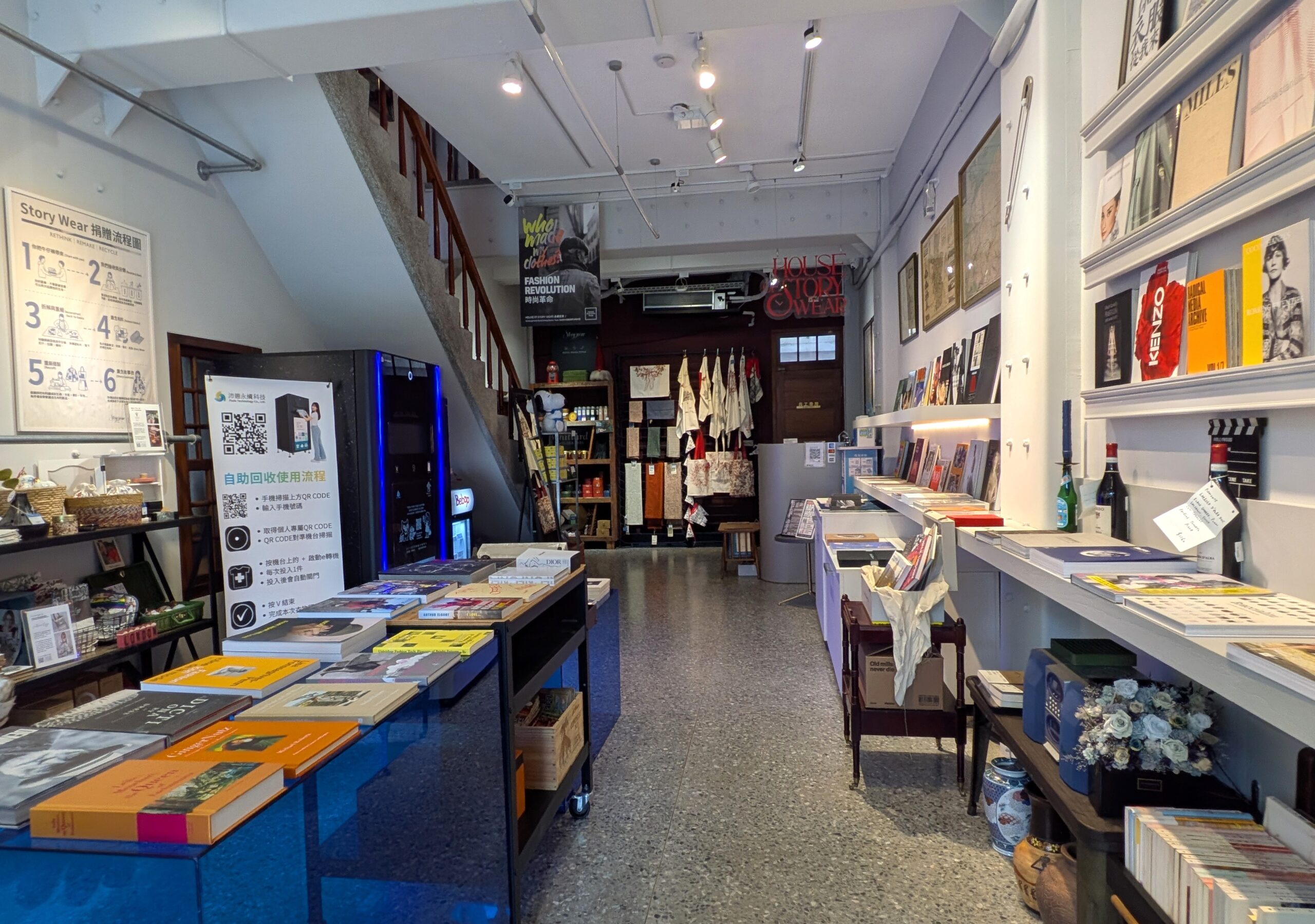 壁面に設けられた書棚と中央の展示台に、デザインやファッションに関する書籍が並ぶショップの内部空間。