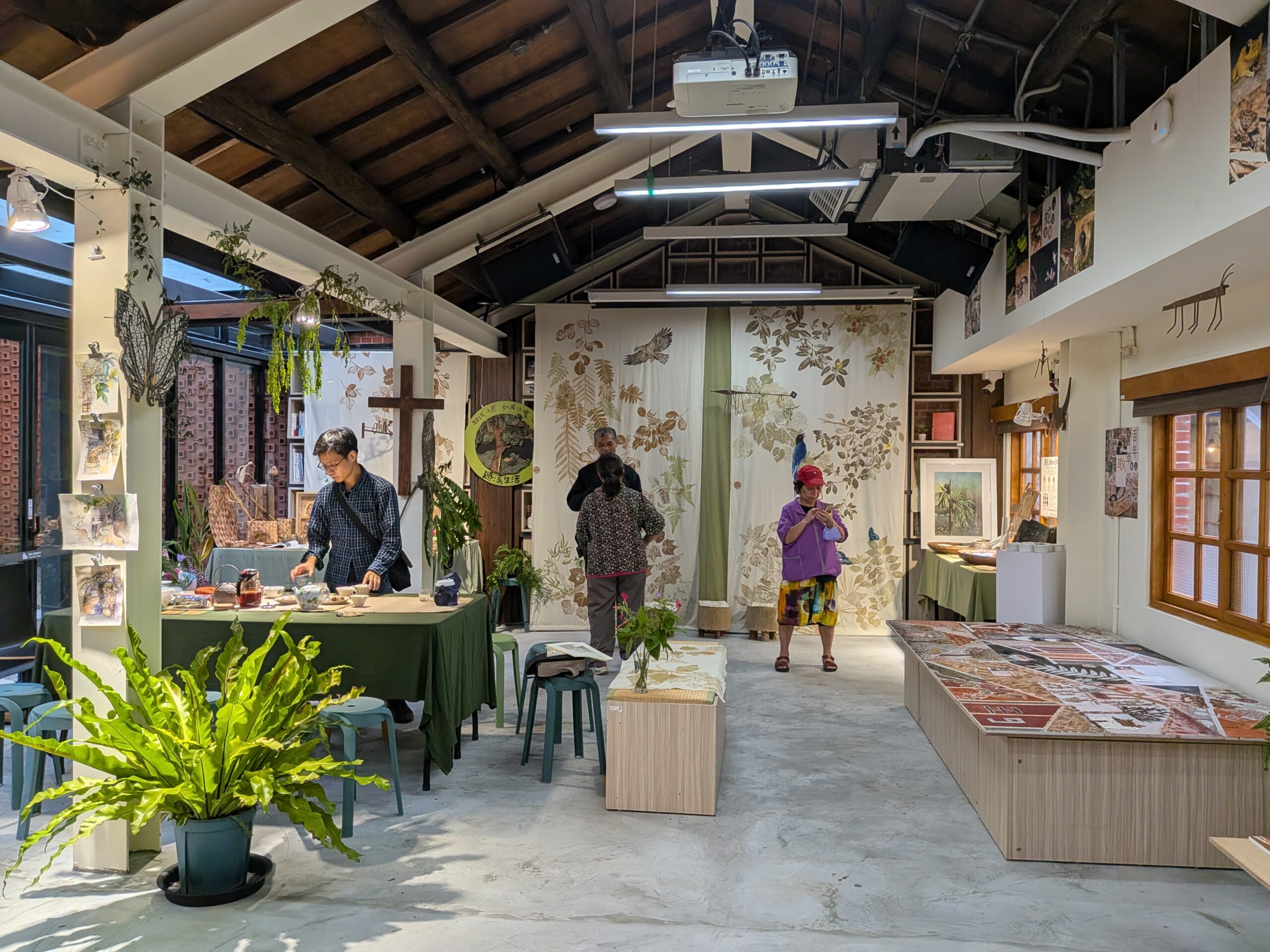煥民新村の木造屋根を生かした展示スペースに、植物や鳥をモチーフにした作品が並ぶ。