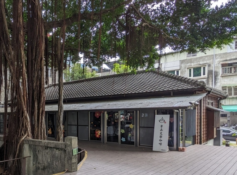 飲食店とショップが並び、ガジュマルの樹が彩りを添える様子
