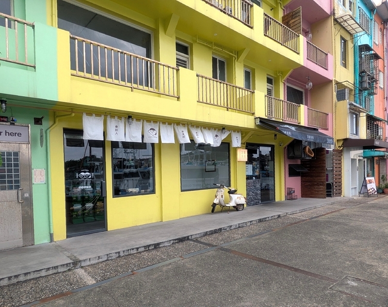 街並みとカフェ 黄色い建物の1階部分にあるカフェとその周辺の街並み。
