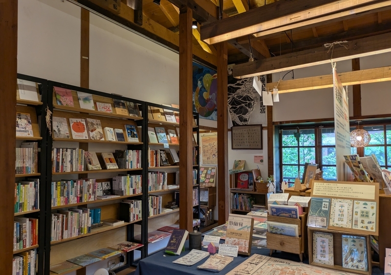 書籍コーナー 壁際の棚に選書が並ぶ書籍販売コーナー。落ち着いた雰囲気の空間。