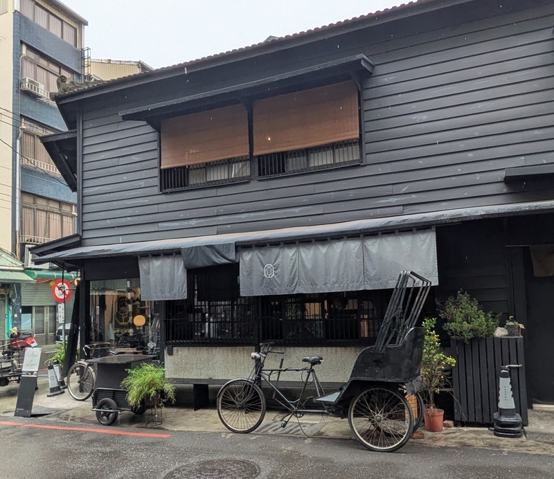 店先の三輪車展示 店の軒先に当時の三輪車や自転車が飾られ、嘉義の街並みに溶け込む新華美西装社の外観。