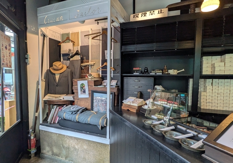 店内展示と団子カウンター 店内には仕立て関連の展示が並び、手前には串団子を提供するカウンターが設けられている。